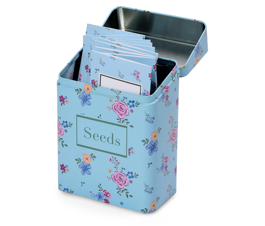 Otwarty, jasnoniebieski pojemnik na nasiona w kwiaty z napisem "Seeds" i kilkoma małymi notatnikami w środku.