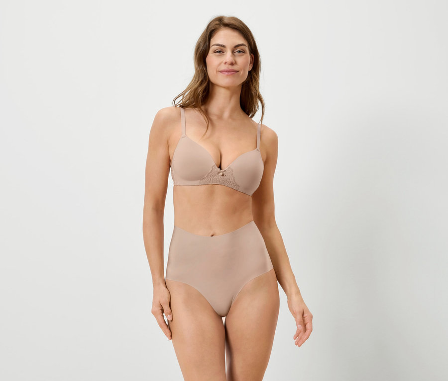 Kobieta ma na sobie beżowy biustonosz i majtki na białym tle.