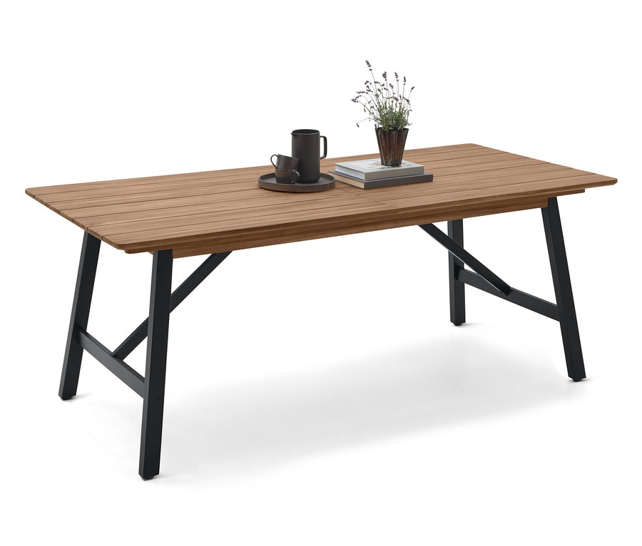 Na drewnianym stole z czarnymi nogami stoi filiżanka, spodek, książka i roślina.