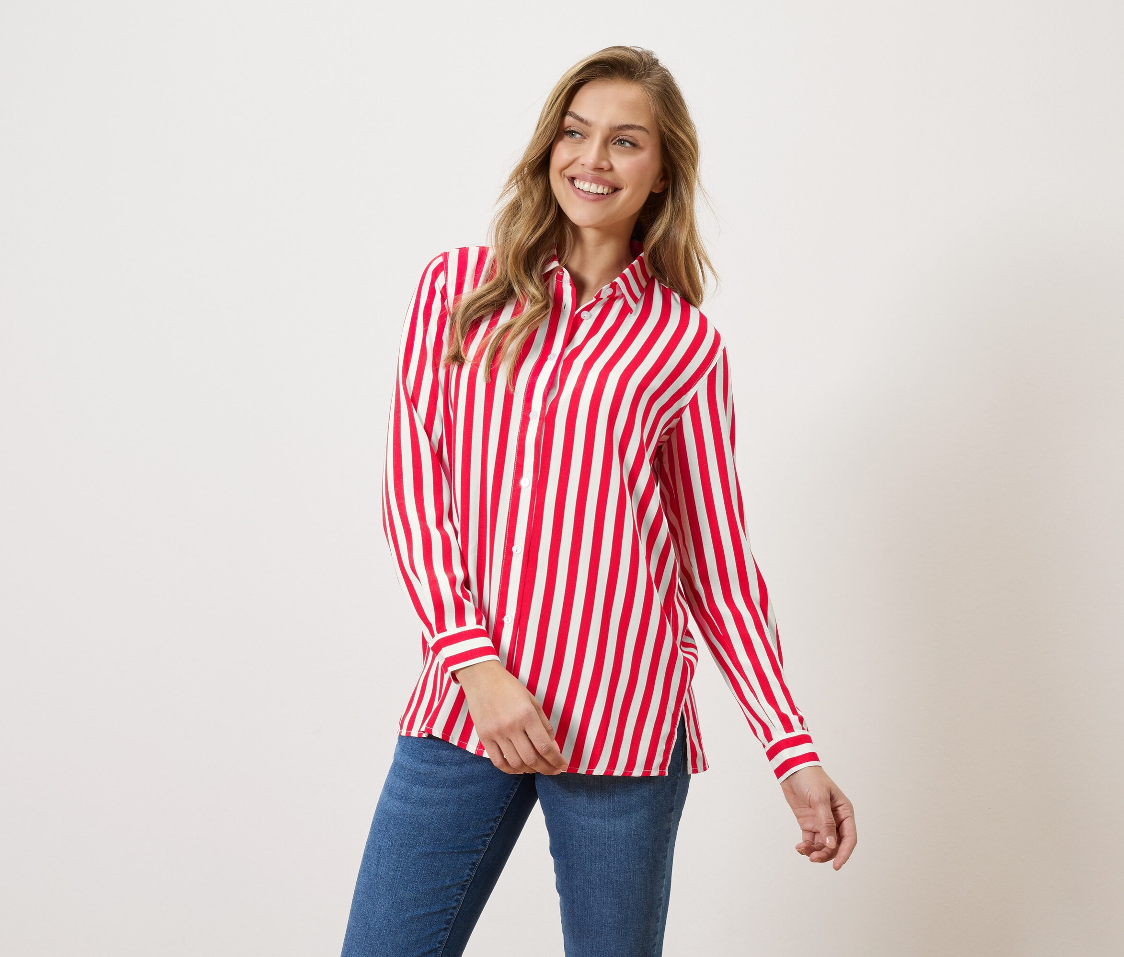 Kobieta ma na sobie koszulę w czerwono-białe paski i dżinsy.