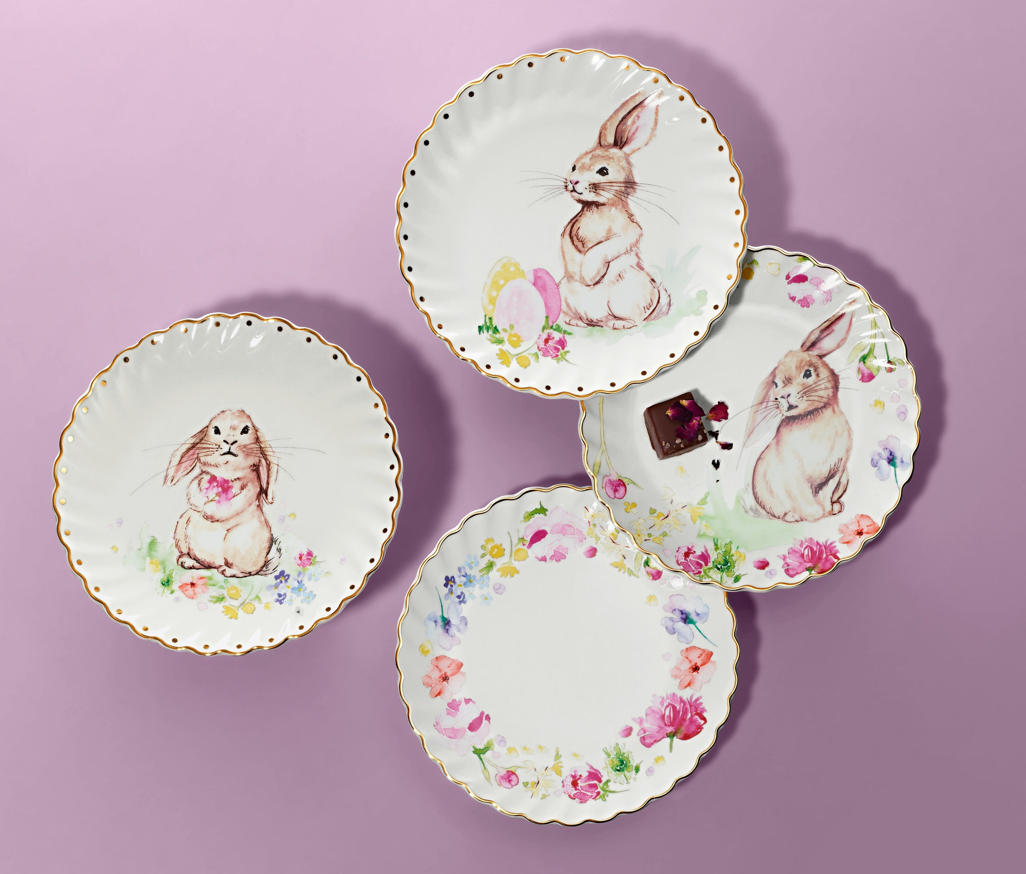 Cztery talerzyki deserowe ze złotym dekorem i wzorami królików na fioletowym tle.