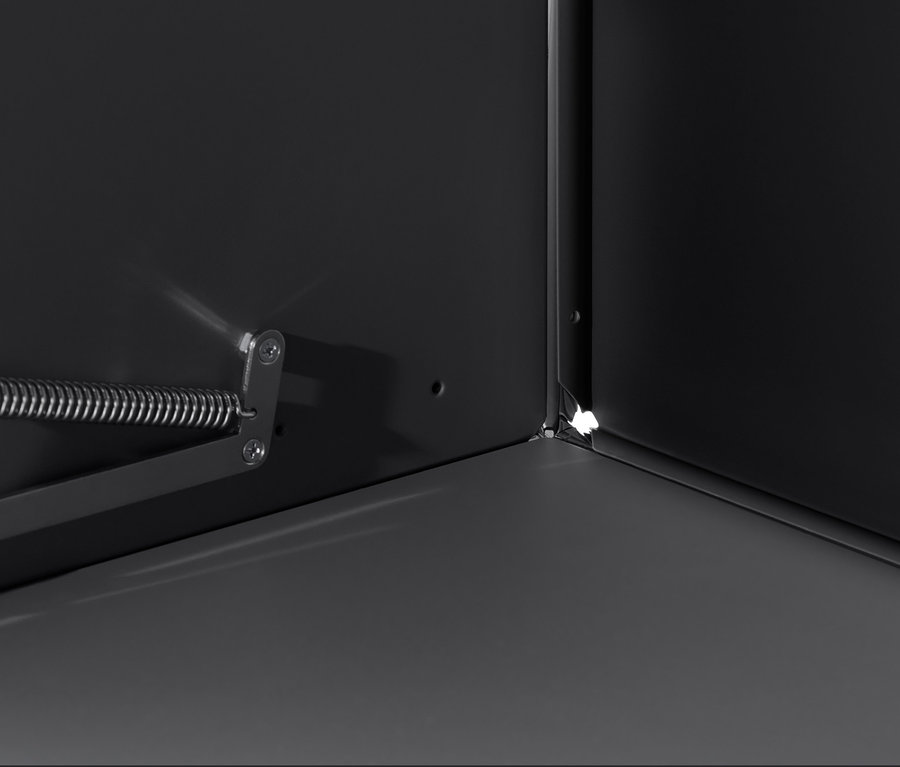 Detal wnętrza czarnej szafki CN3 z klapą, z widocznym rogiem i mechanizmem otwierania.