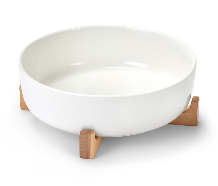 Biała, porcelanowa forma do zapiekania na drewnianym stojaku.