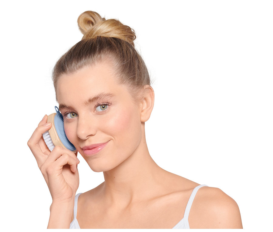 Kobieta używa szczoteczki do twarzy.