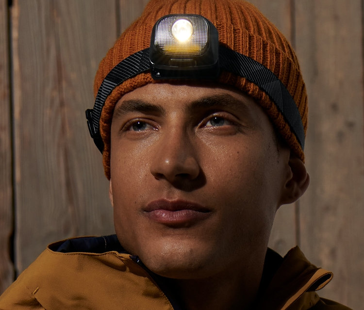 Mężczyzna ma na sobie brązową czapkę i latarkę czołową.