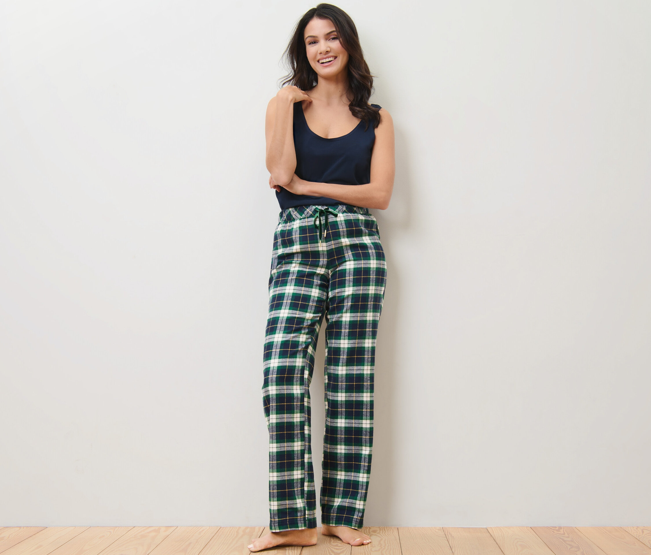 Kobieta pozuje w zielonych flanelowych spodniach rekreacyjnych.