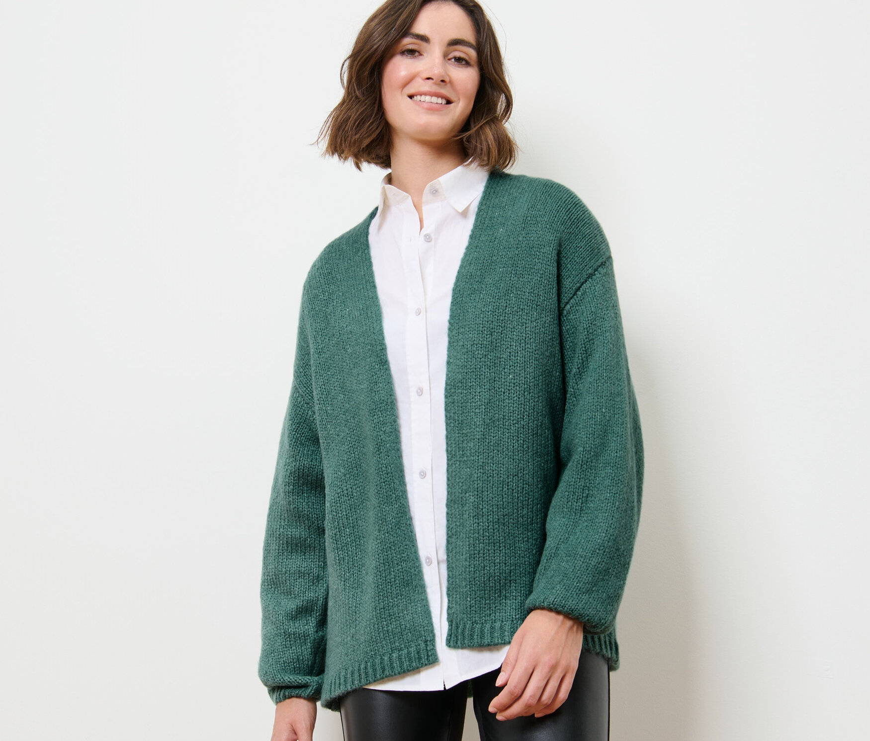 Kobieta ma na sobie kardigan bez zapięcia o grubym splocie.