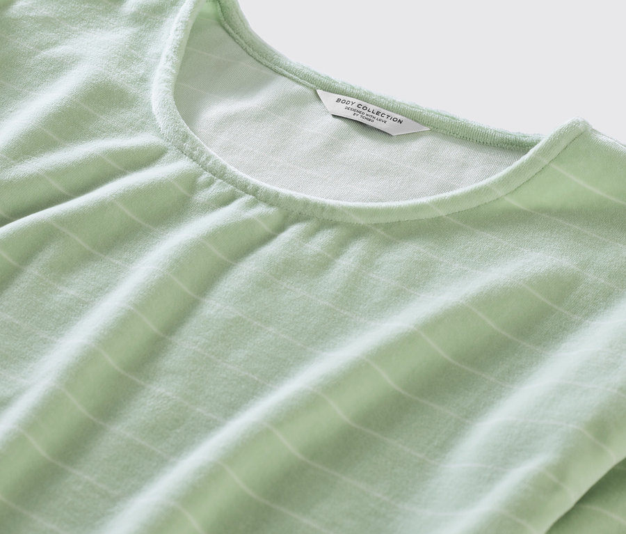 Zbliżenie na zieloną piżamę z weluru w białe paski.