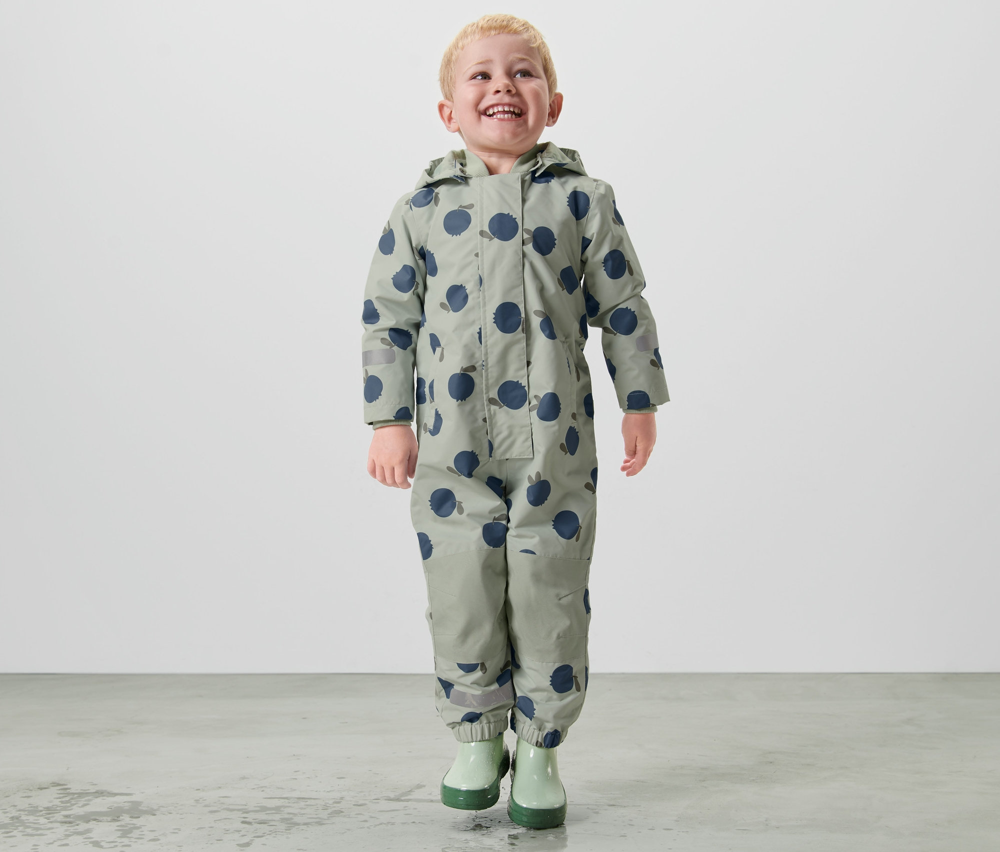 Chłopiec idzie w kombinezonie przeciwdeszczowym.