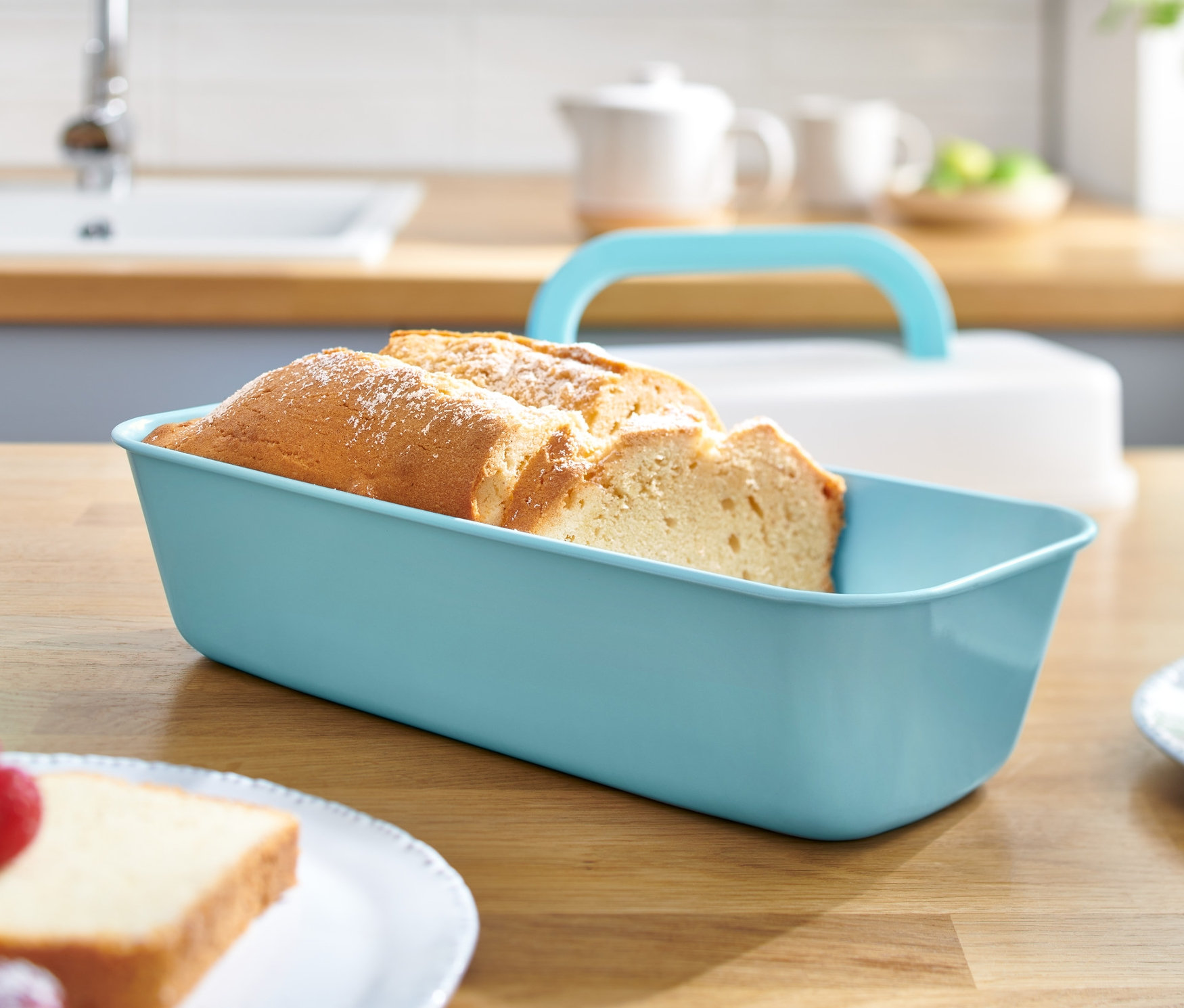 Pokrojony chleb w prostokątnej formie do pieczenia z pokrywką na drewnianym stole.