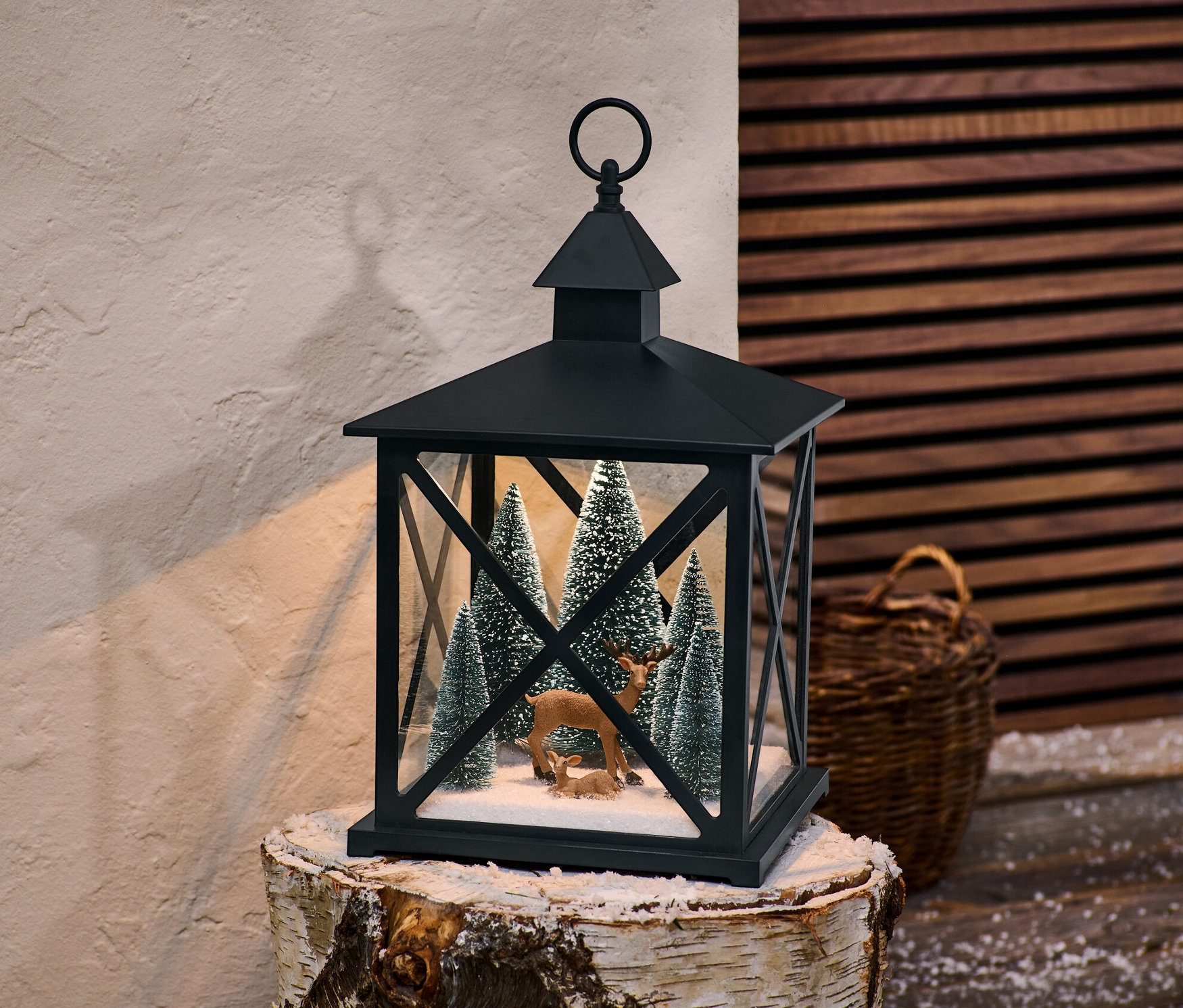 Latarnia dekoracyjna LED stoi na pniu brzozy, wewnątrz drzewka i figurki zwierząt.