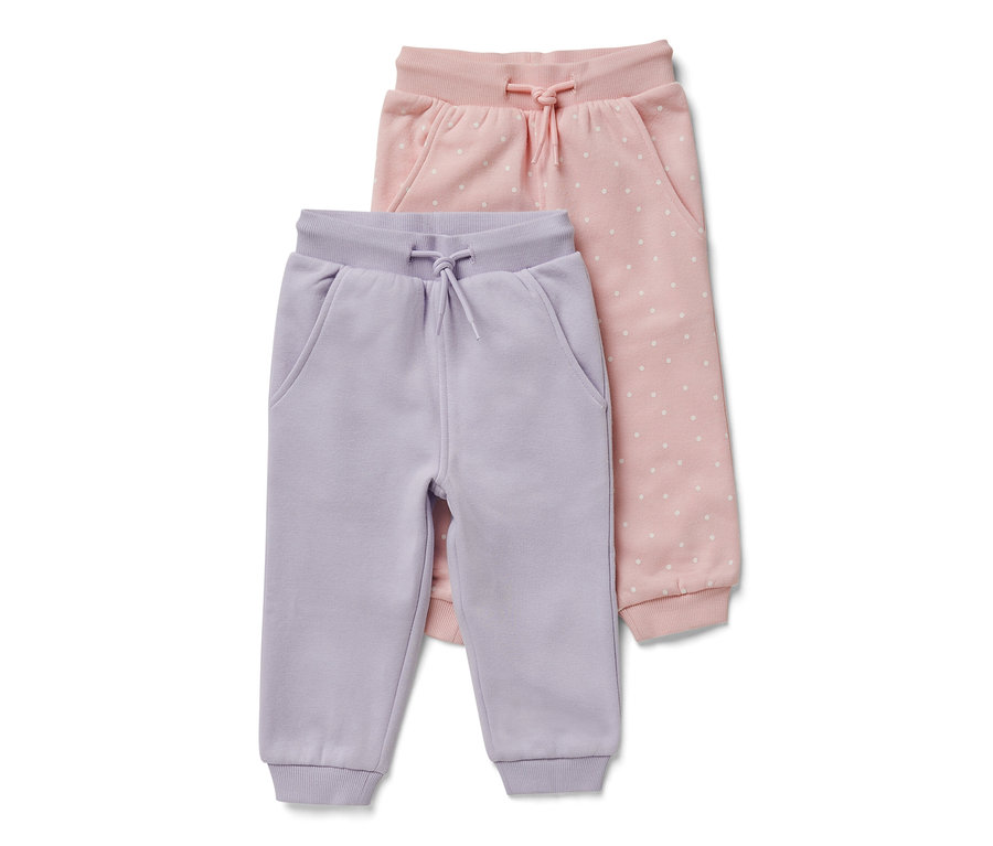 Dwie pary niemowlęcych spodni dresowych: jedna jasnofioletowa, a druga różowa w białe kropki.