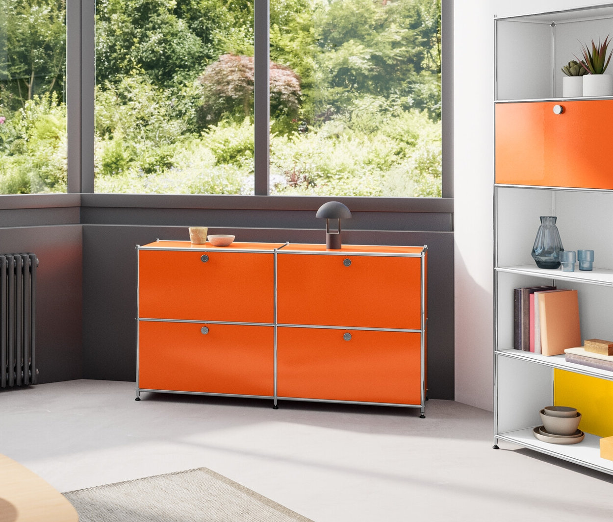 Wnętrze z drewnianym stołem, metalową szafką typu sideboard »CN3« z 4 przegródkami z klapami, wysokim metalowym regałem »CN3« z 2 przegródkami z klapami i drewnianą lampą wiszącą.