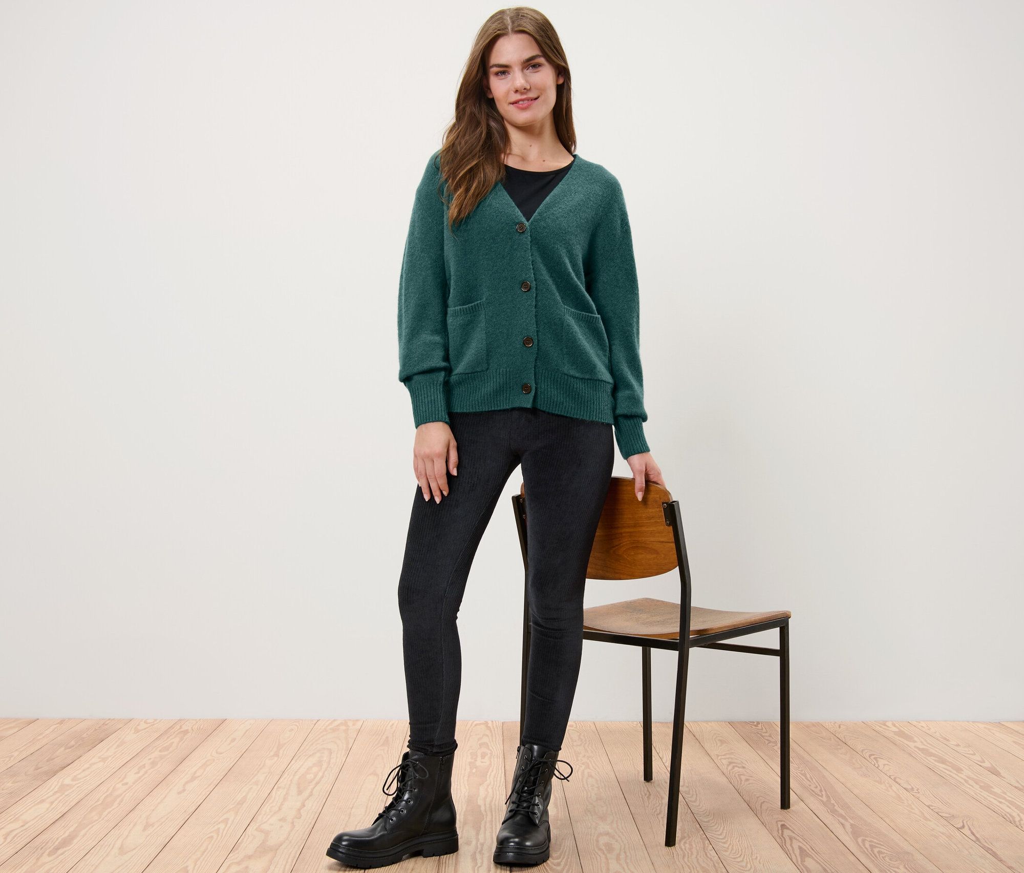 Kobieta stoi w ciemnozielonym rozpinanym swetrze z zawartością wełny.