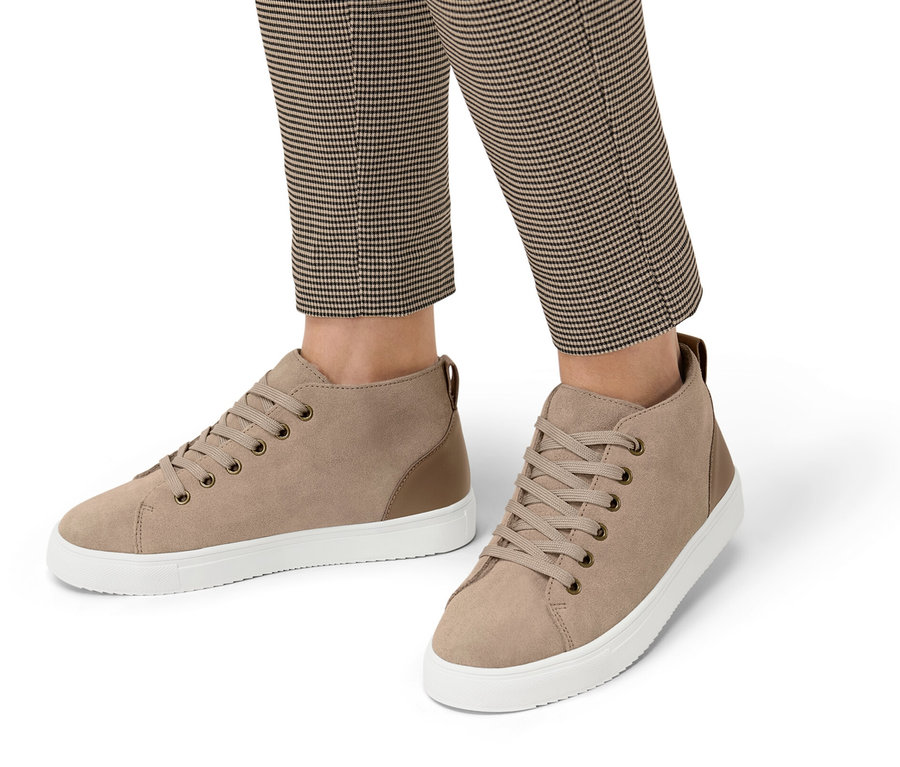 Nogi osoby w spodniach w kratę, ubrane w buty typu sneakers ze skóry welurowej z wyściółką.