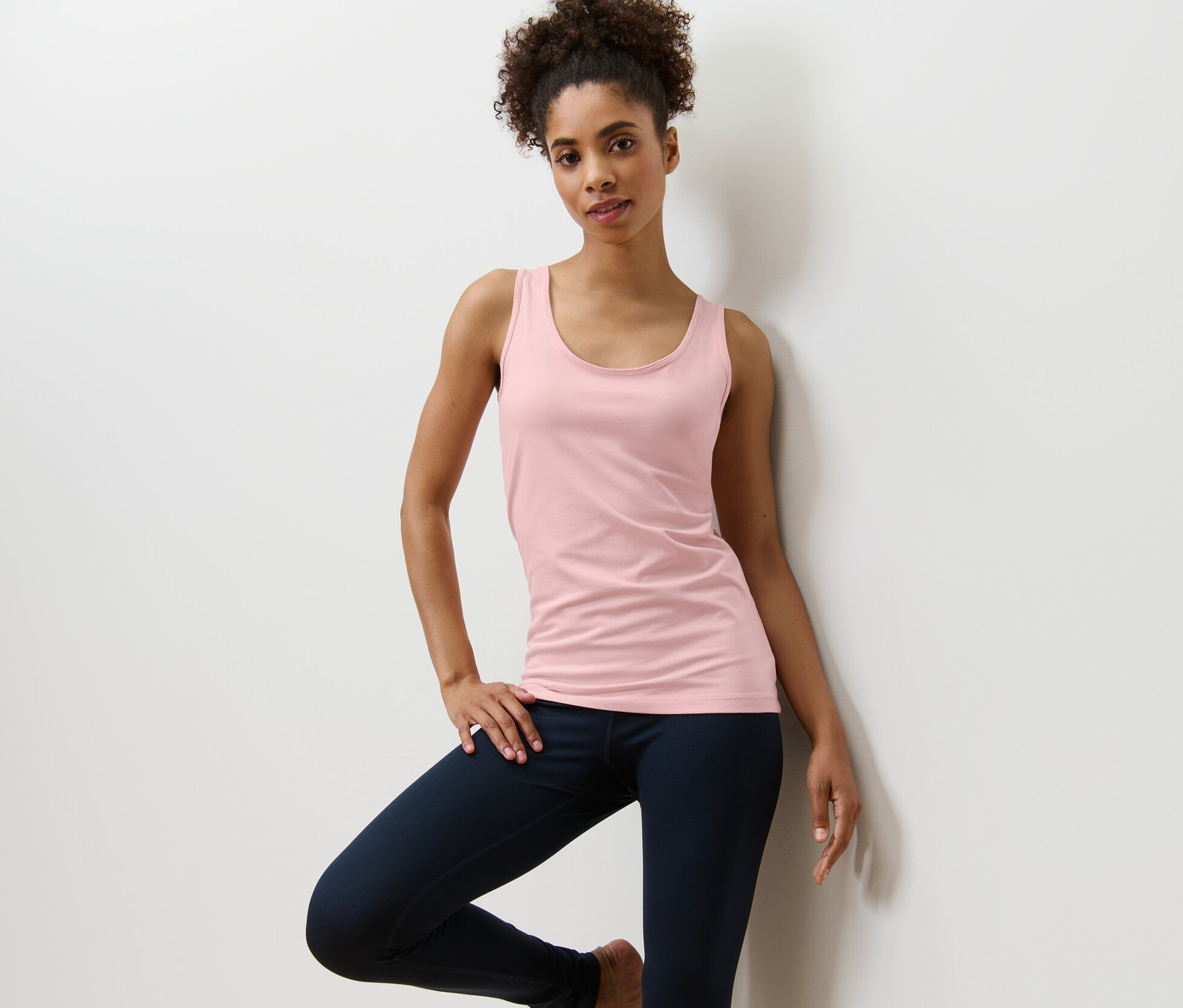 Kobieta pozuje w bladoróżowym topie z 2-częściowego zestawu.