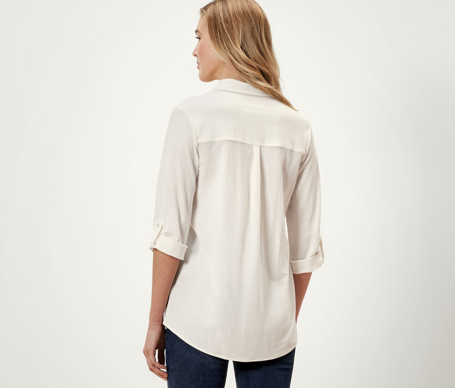 Widok z tyłu kobiety w kremowobiałej bluzce z dżerseju piqué i niebieskich dżinsach.