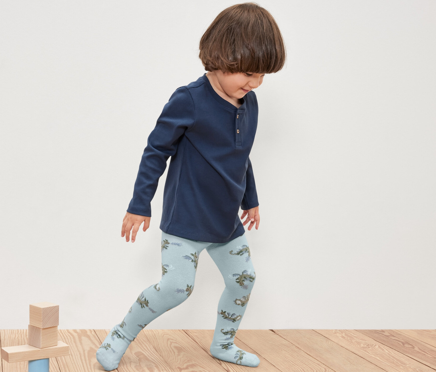 Chłopiec bawi się drewnianymi klockami, ubrany w rajstopy dziecięce, 5 par, rycerz.