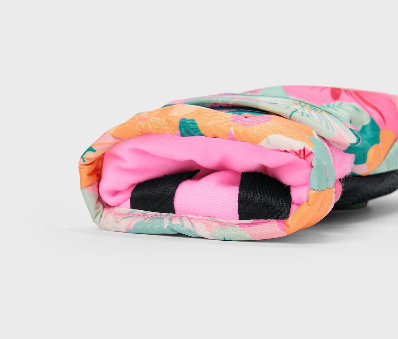 Szczegół kolorowego pokrowca z tropikalnym wzorem i różowym wnętrzem.