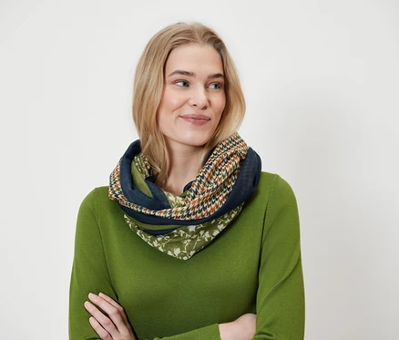 Blondynka nosi wielokolorowy szal i zielony sweter.