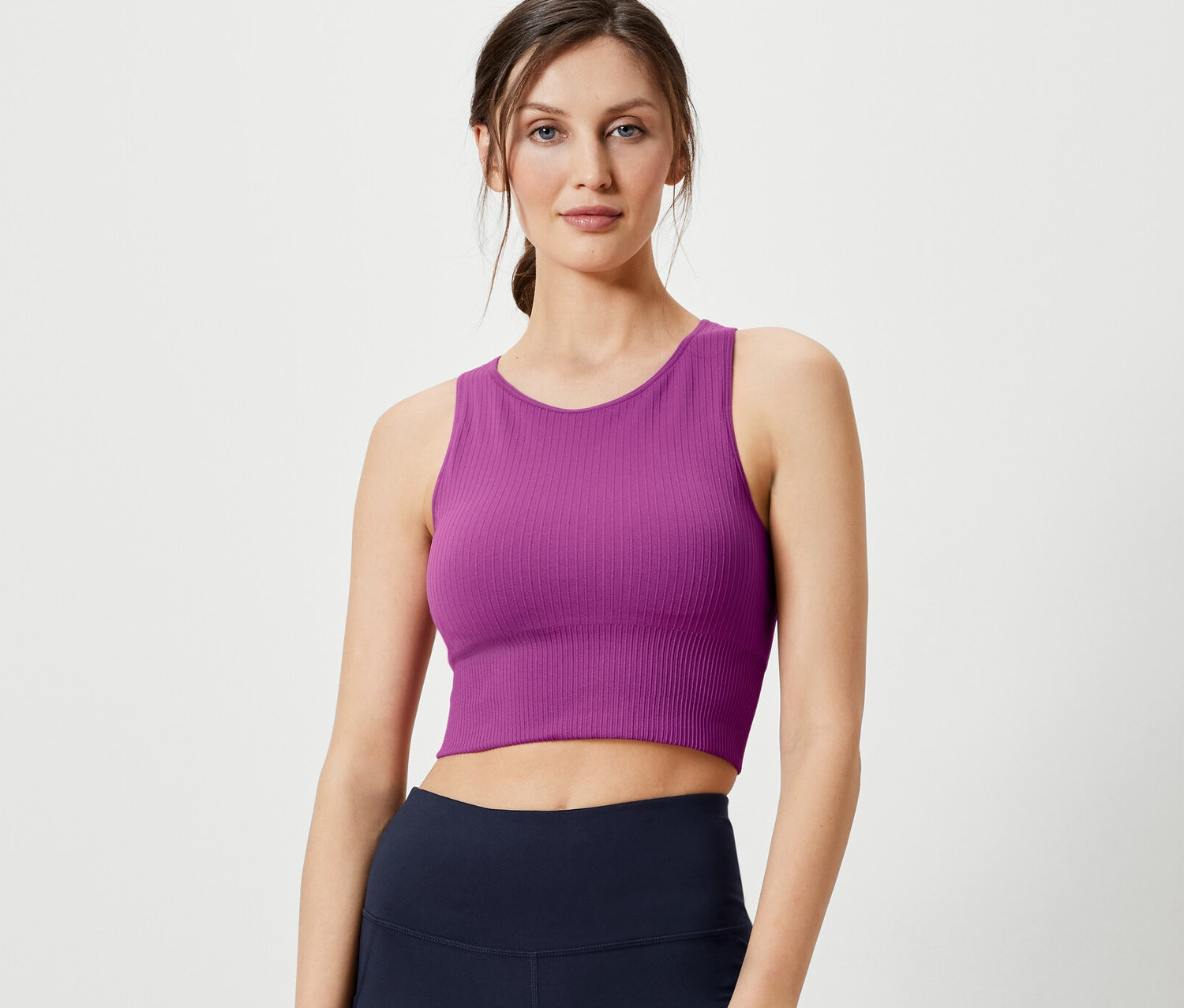 Kobieta pozuje w bezszwowej braletce sportowej i granatowych legginsach.