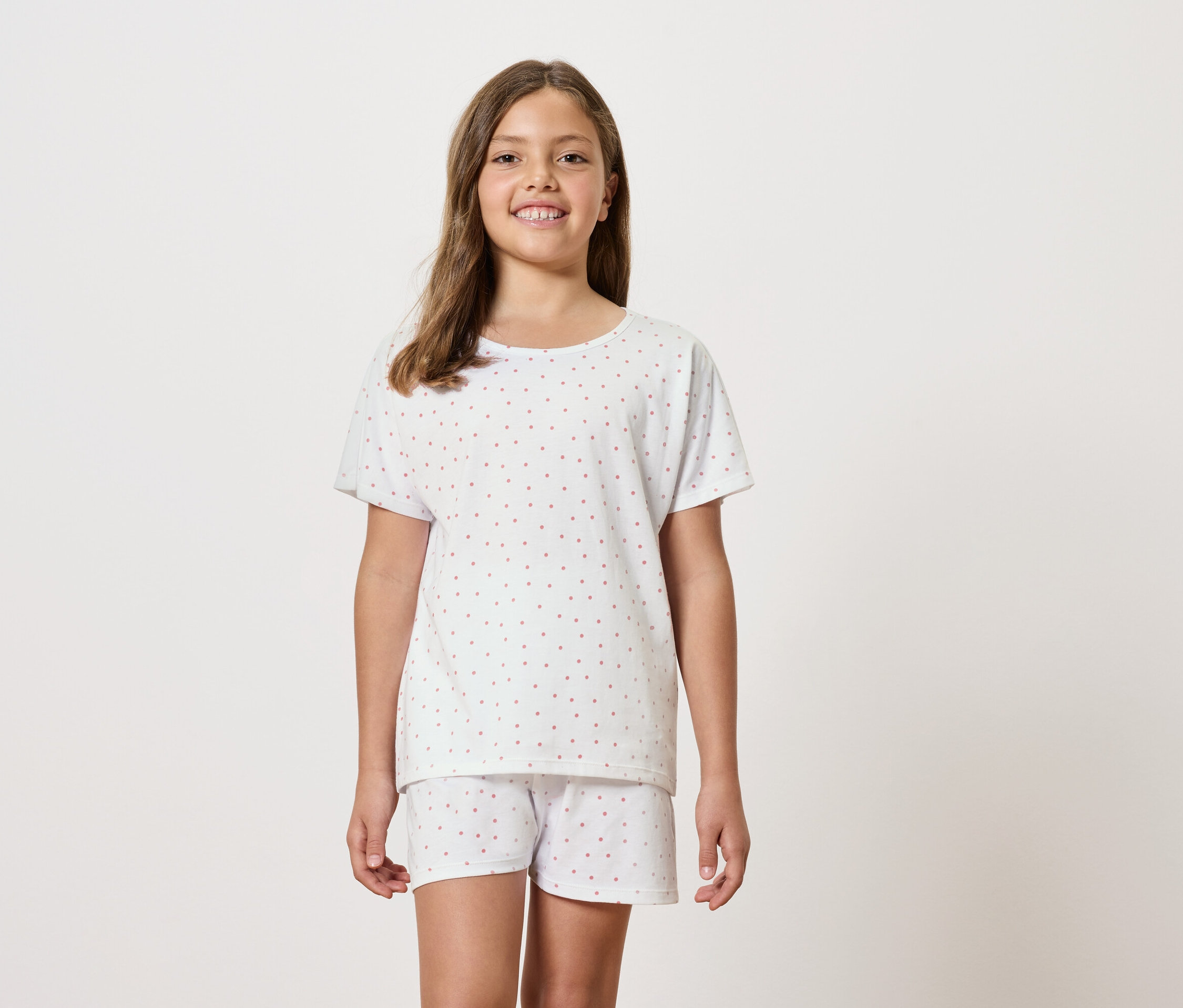Dziewczyna ma na sobie białą piżamę z krótkim rękawem i szortami.