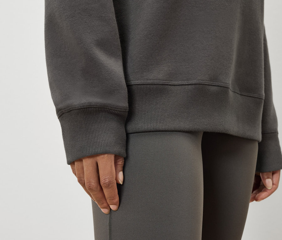 Zbliżenie na kobietę w szarej bluzie i legginsach.