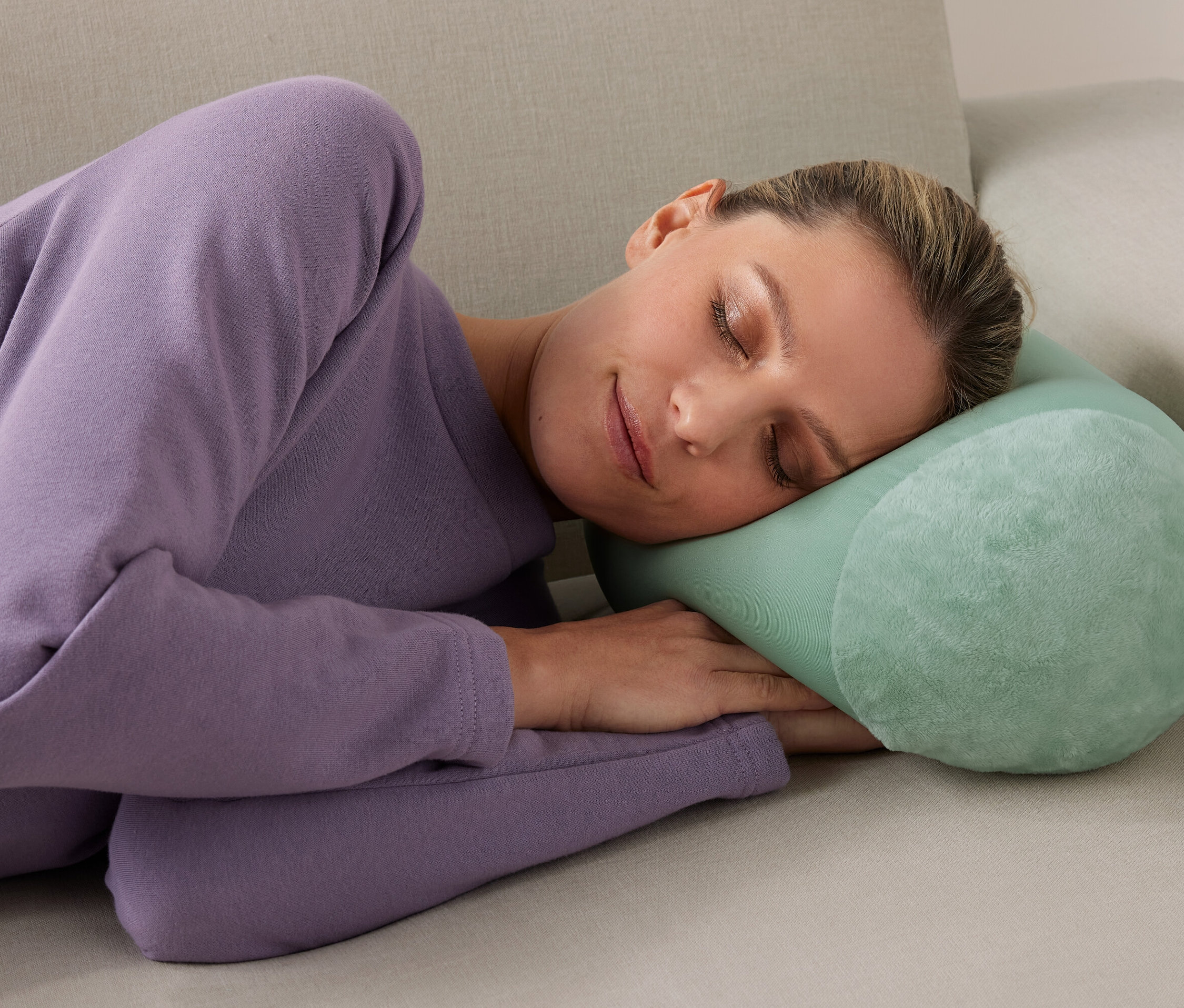 Kobieta śpi na kanapie z poduszką relaksacyjną.