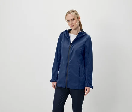 Kobieta pozuje w granatowej kurtce softshell z kapturem i granatowych spodniach.