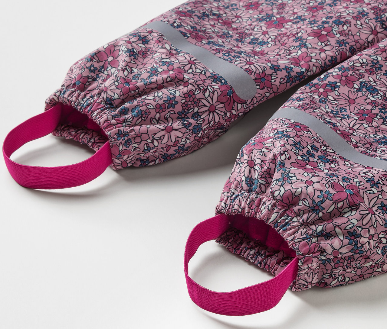 Zbliżenie na termoaktywne spodnie przeciwdeszczowe w kwiaty z elementami odblaskowymi.