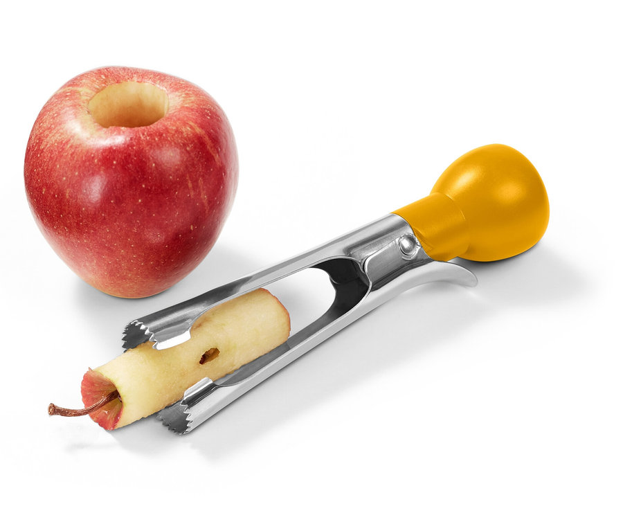 Czerwone jabłko z wydrążonym środkiem stoi obok wykonanego ze stali nierdzewnej drylownicy do jabłek z żółtą rączką, która usuwa gniazdo nasienne z drugiego jabłka.
