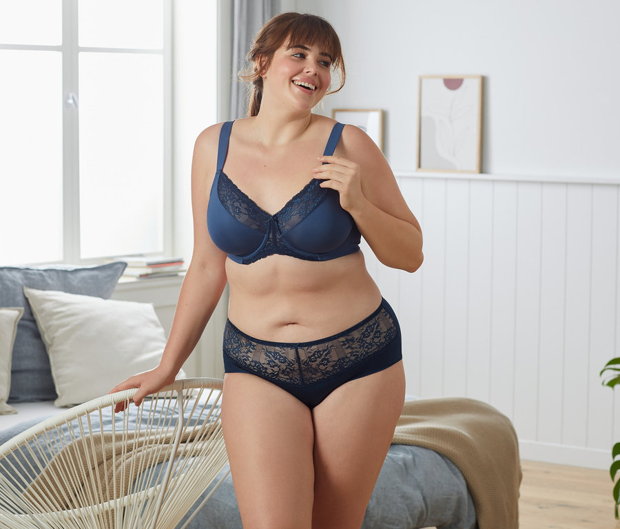 Kobieta pozuje w niebieskim biustonoszu minimizer.