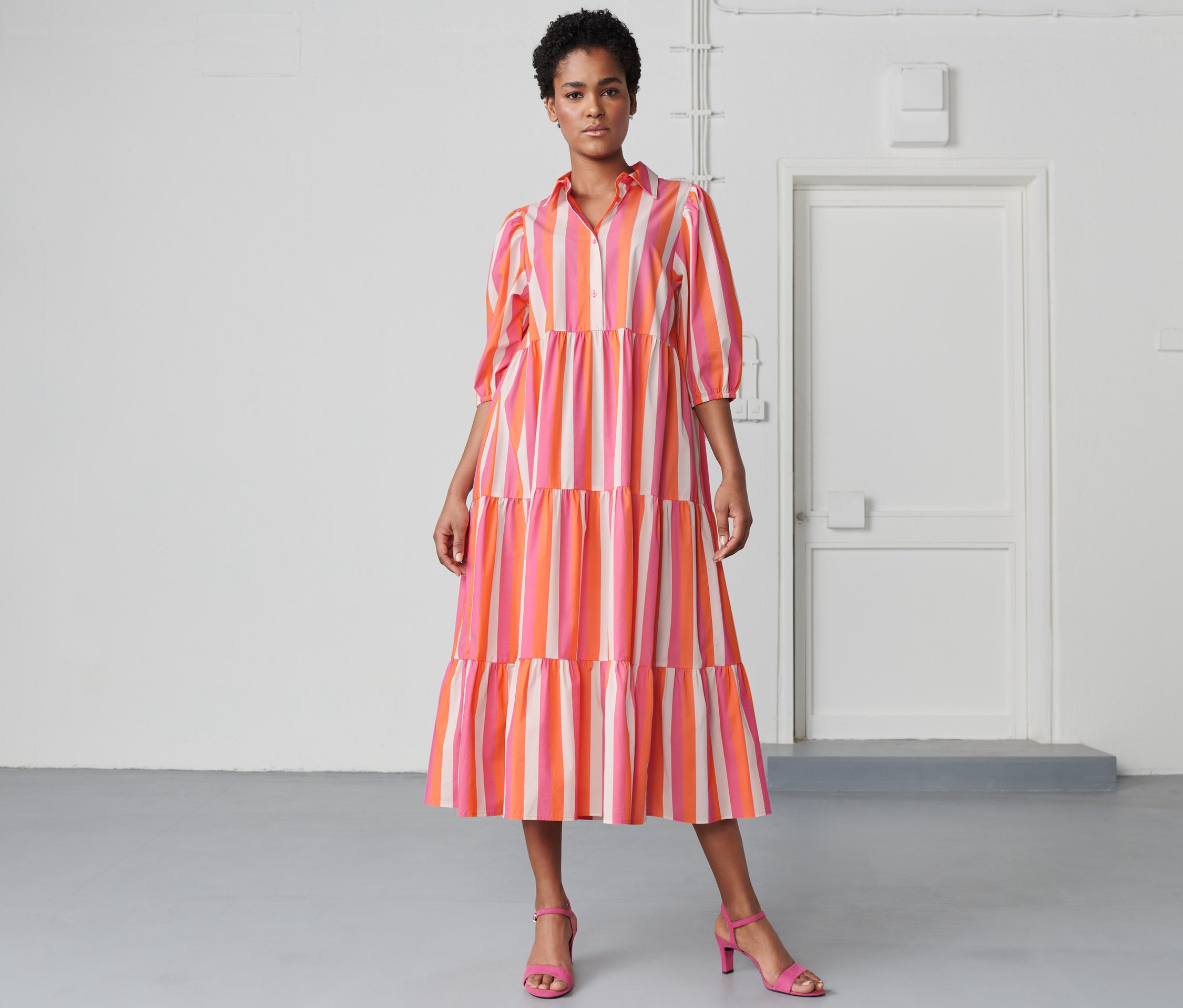 Kobieta pozuje w sukience z tkaniny w paski.