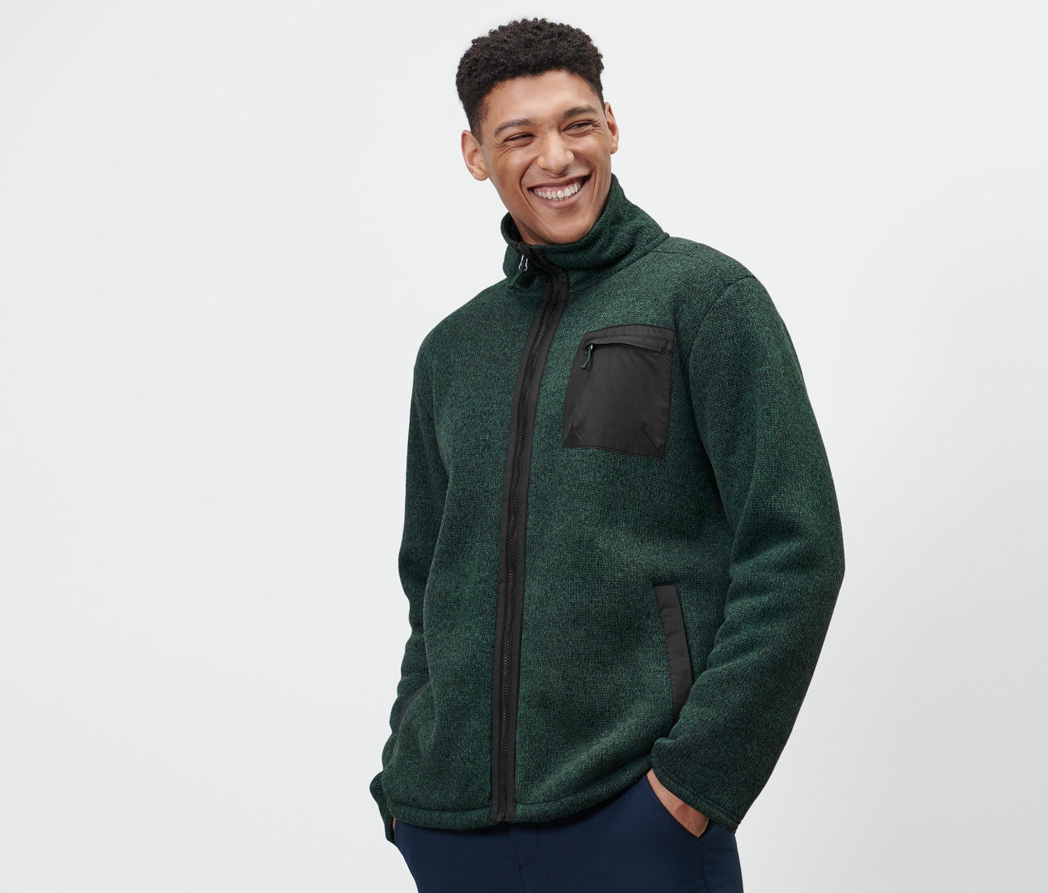 Mężczyzna ma na sobie zieloną termoaktywną bluzę z dzianiny polarowej i granatowe spodnie.