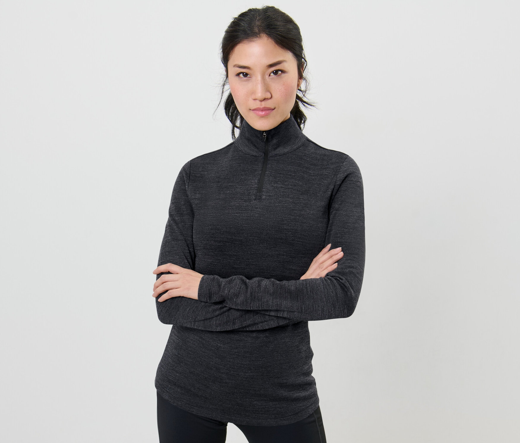 Kobieta pozuje ze skrzyżowanymi ramionami, ubrana w koszulkę funkcyjną z wełną z certyfikatem RWS.