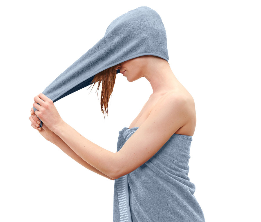 Kobieta zakłada na głowę jasnoniebieski ręcznik turban.