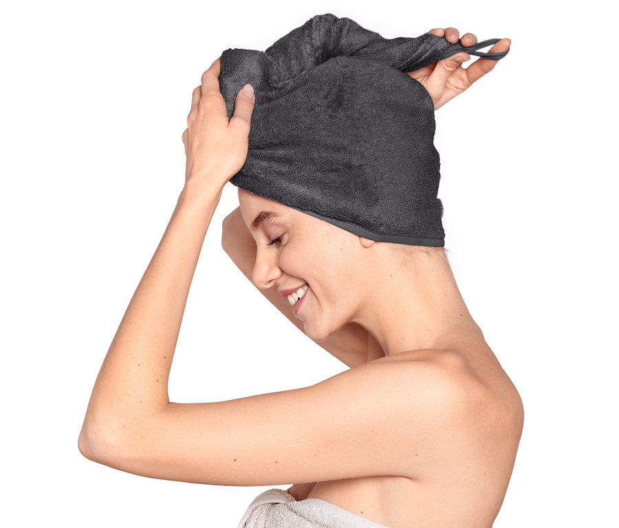 Kobieta zakłada na głowę antracytowy ręcznik-turban.