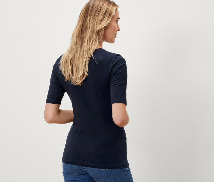 Kobieta ma na sobie granatową koszulkę z półdługim rękawem.