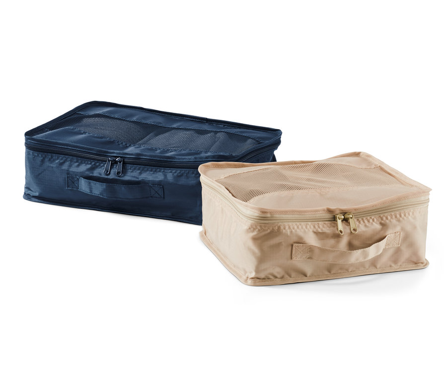 Dwa organizery podróżne, jeden granatowy i jeden beżowy, leżą obok siebie.