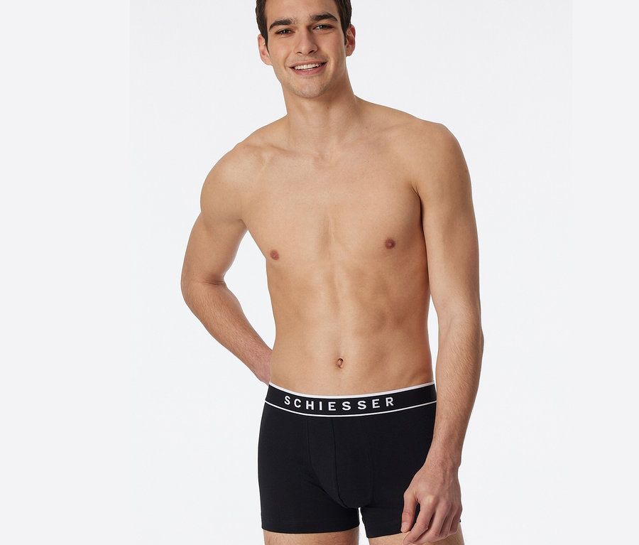Mężczyzna pozuje w czarnych bokserkach z bawełny ekologicznej SCHIESSER, 3 sztuki.