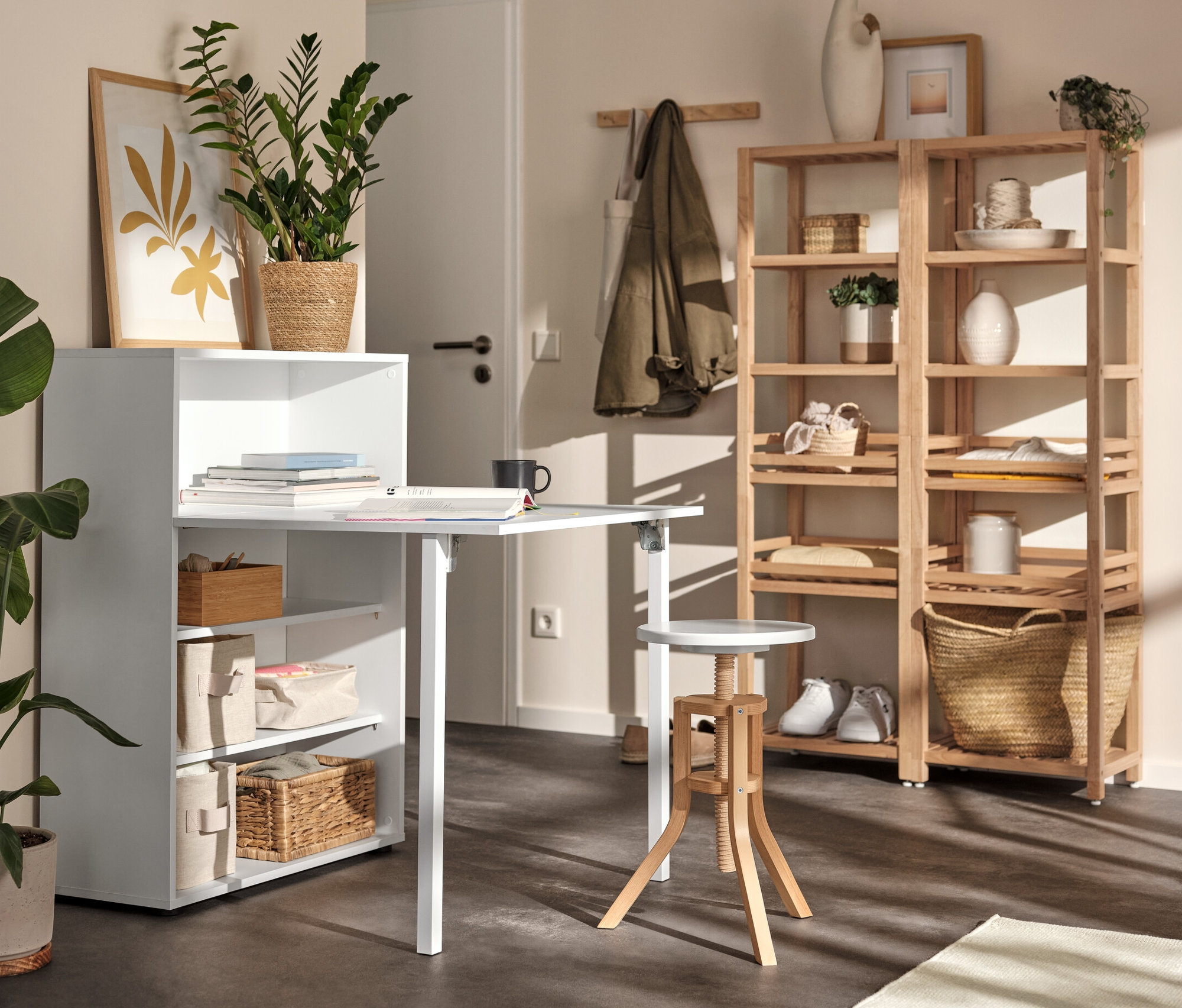 Biała szafka z rozkładanym stolikiem, regał z litego drewna i stołek o regulowanej wysokości w pokoju.