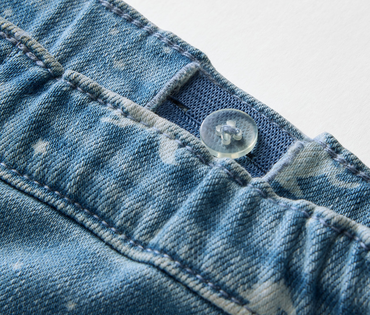 Zbliżenie na dziecięce tregginsy z guzikiem i regulowaną gumką w pasie.