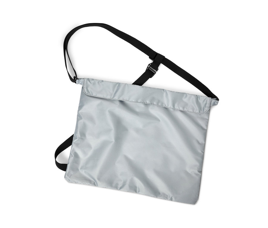 Pionowy kadr srebrnej torby zakupowej na rower z czarnymi paskami na białym tle.