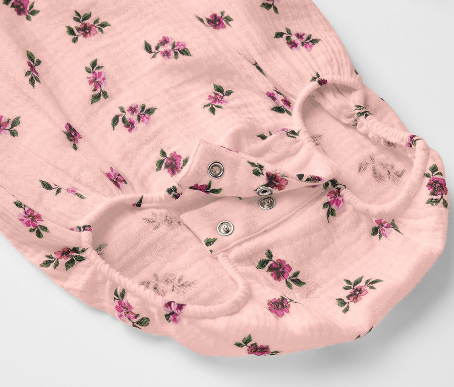 Zbliżenie na muślinowe body z kwiatowym wzorem zapinanym na zatrzaski.