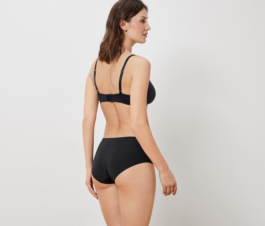 Kobieta tyłem do kamery ma na sobie czarny biustonosz i majtki.