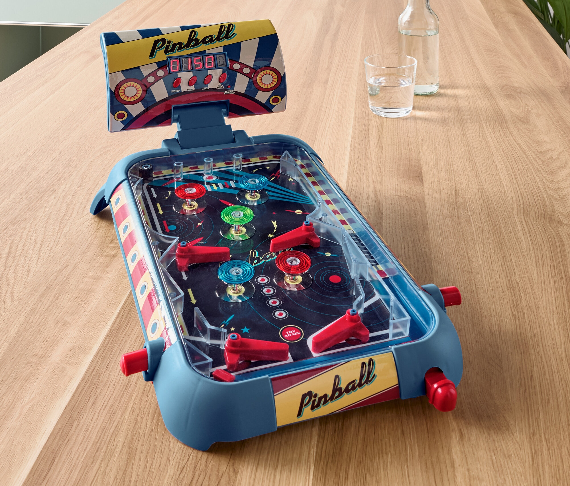 Niebieski mini flipper na drewnianym stole.