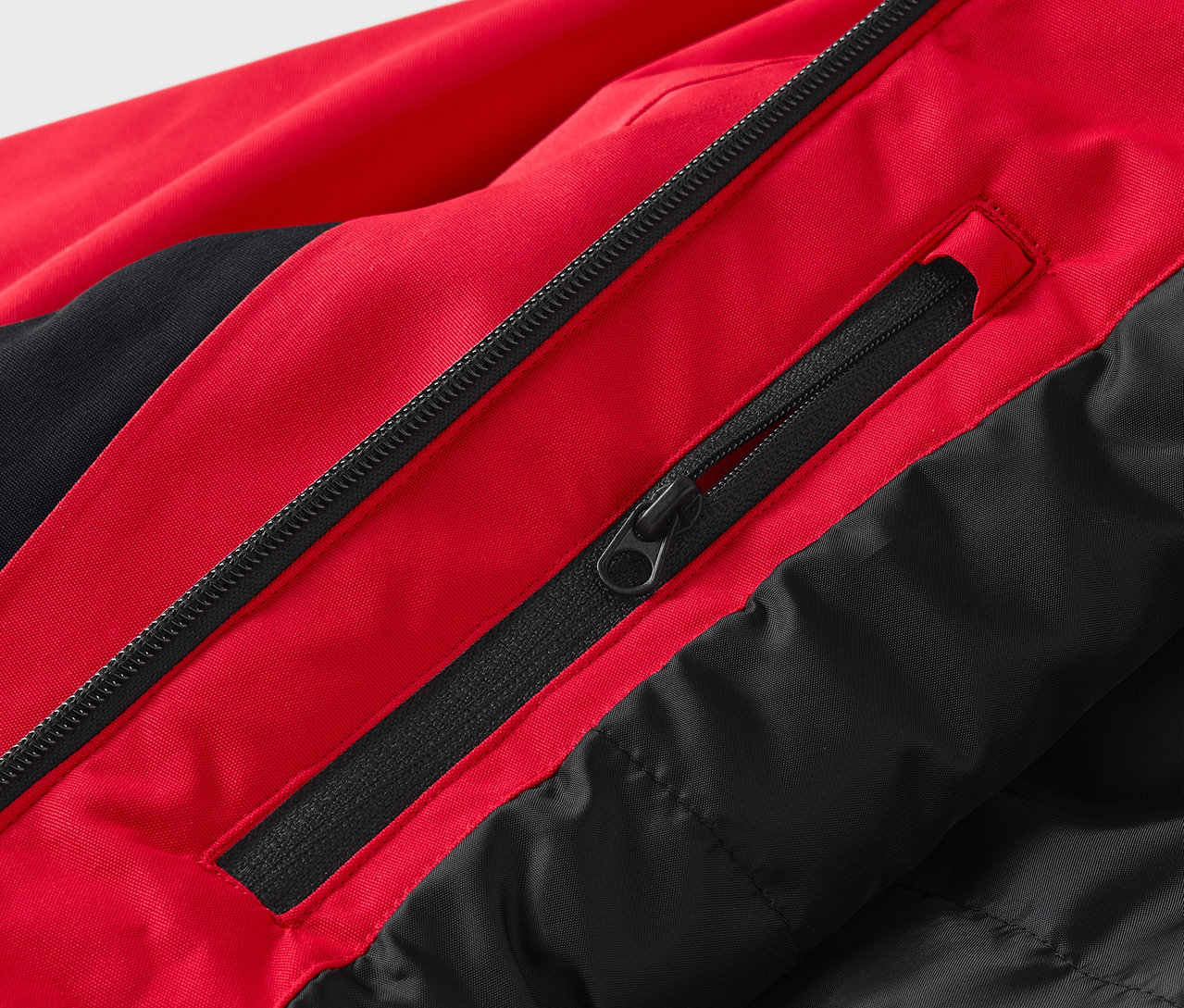 Zbliżenie na czerwono-czarną kurtkę z zamkami błyskawicznymi.