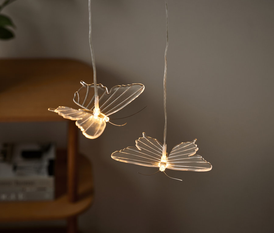 Dwie lampy w kształcie motyli wiszą z sufitu.