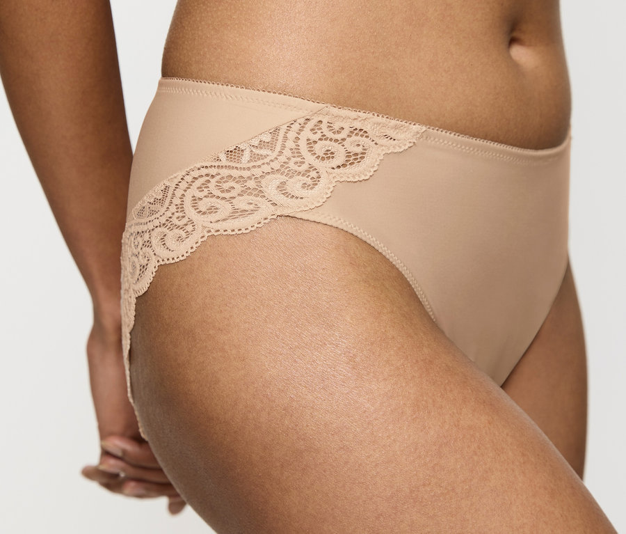 Zbliżenie ciała kobiety ubranej w figi Triumph Amourette Tai w kolorze skóry z koronką.