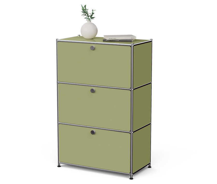 Zielona szafka z trzema szufladami, na której stoi wazon z rośliną i książka.